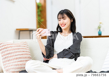 スマホで動画を見る若い女性 スマホで動画を見る若い女性 79663756