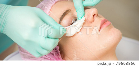 Young woman receiving eyelash removal procedure and removes mascara with a cotton swab and stick in a beauty salon. Young woman receiving eyelash removal procedure and removes mascara with a cotton swab and stick in a beauty salon. 79663866