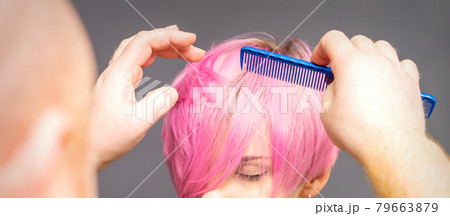 Professional hairdresser checks hairstyle with a comb of young beautiful caucasian woman. 79663879