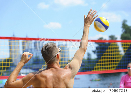 Beach volleyball. Male volley player hitting over the net ball attacking 79667213