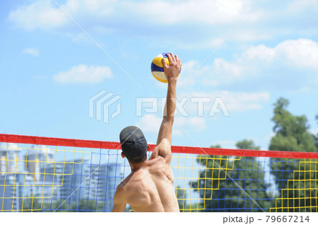 Beach volleyball. Male volley player hitting over the net ball attacking Beach volleyball. Male volley player hitting over the net ball attacking 79667214