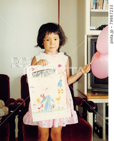 昔のフィルム写真　お絵かきの絵を見せる幼稚園の女の子 79667233