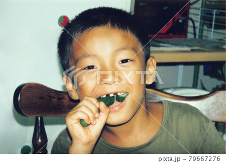 昔のフィルム写真　きゅうりを食べる小学生の男の子 79667276