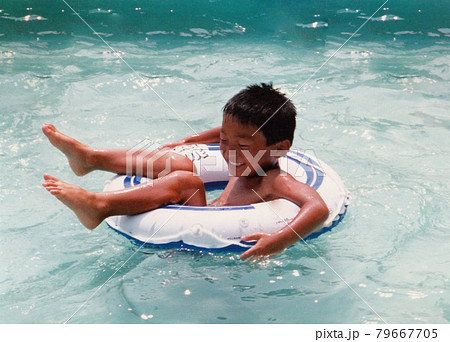 昔のフィルム写真　プールで遊ぶ　浮き輪を持った男の子 79667705