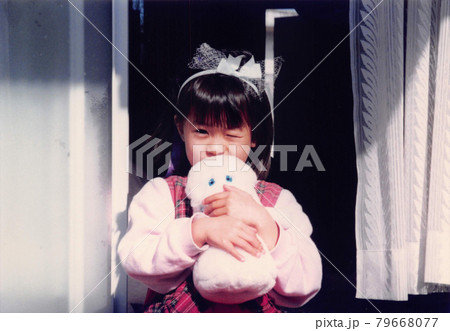 昔のフィルム写真　ぬいぐるみを持ってウインクする女の子 79668077