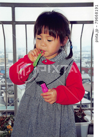昔のフィルム写真　シャボン玉で遊ぶ三つ編みの女の子 79668191