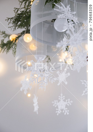 Christmas interior decoration. White knitted snowflakes, fir branches and christmas lights on a chandelier Christmas interior decoration. White knitted snowflakes, fir branches and christmas lights on a chandelier 79668309