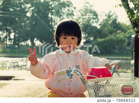 昔のフィルム写真　補助輪付き自転車に初めて乗る女の子 79668522