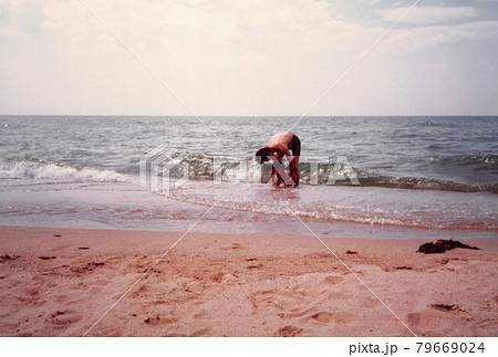 昔のフィルム写真　海で遊ぶ父親と小さい男の子 79669024