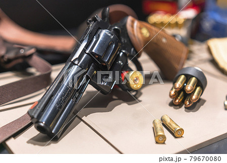弾丸で聳えたスピードローダーとリボルバーのコルトパイソン357マグナムのレプリカ。 79670080