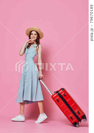 woman in blue dress with red suitcase travel destination pink background 79670189