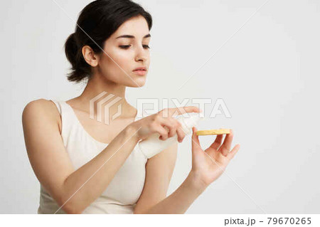 pretty brunette in a white tank top sponge in hands clean skin face care 79670265