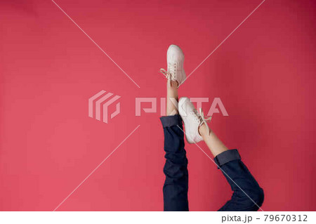 female legs in white sneakers upside-down view pink background fashion 79670312