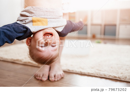 Mother holding upside down her laughing child. 79673202