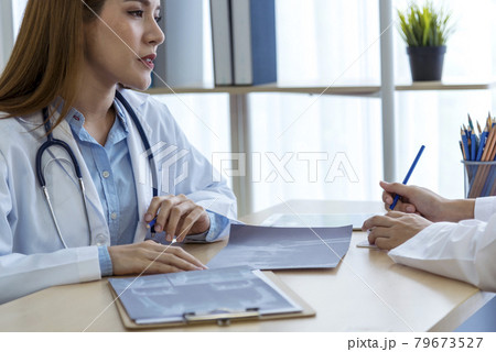 Two asian women doctors discuss meeting doctor's office medical clinic looking x-ray film consulting patient disease. Asian medical lab young women talking together discussing healthcare teamwork 79673527