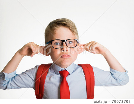 Funny smart kid boy in school uniform pulling ears and showing tongue isolated on white background. Student making monkey face. Funny silly child boy grimacing 79673702