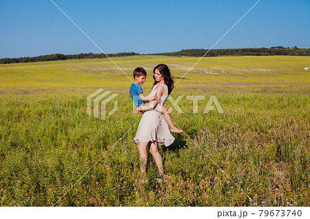 mother holds her son in her arms in the field in nature mother holds her son in her arms in the field in nature 79673740
