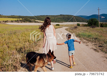 mother and son walk along the rural road to the field mother and son walk along the rural road to the field 79673742