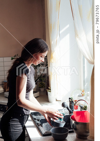 a woman housewife washes dishes in the kitchen a woman housewife washes dishes in the kitchen 79673765
