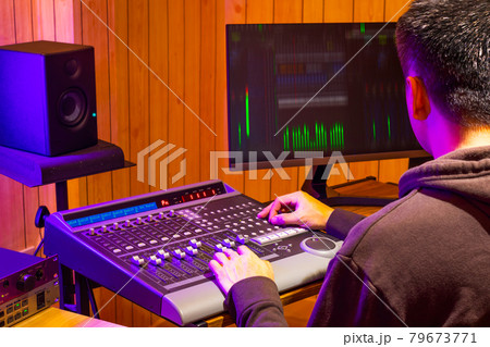 back of asian professional sound engineer mixing audio signal on control surface mixing console in broadcasting, recording studio 79673771