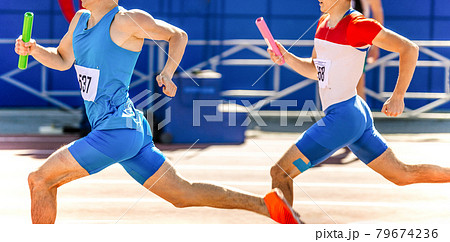 two male athletes with relay baton in hands run at competition 79674236