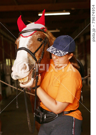 teenager girl in stable brush horse before daily riding outside. 79674954
