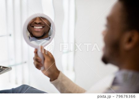 New Smile. Black Man Looking At Mirror While Sitting In Dentist Chair 79676366