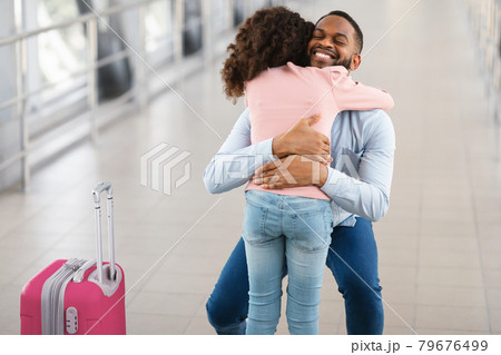 Happy black man hugging his daughter in airport Happy black man hugging his daughter in airport 79676499