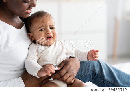 Black lady holding crying baby with colic on hands Black lady holding crying baby with colic on hands 79676510