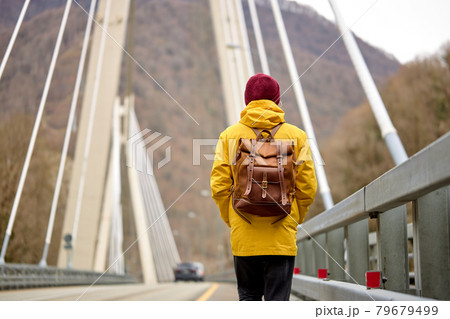 Rear view on man crosses bridge on the river, outdoor activity, travel concept 79679499