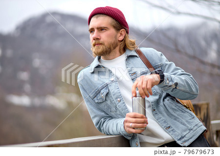 caucasian handsome brutal bearded man traveling in the wild nature with thermos 79679673