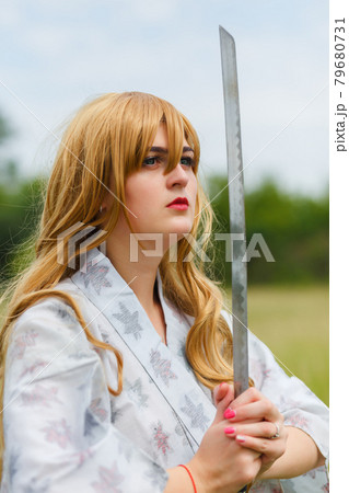 Asian woman holding a sword in a warrior position. 79680731