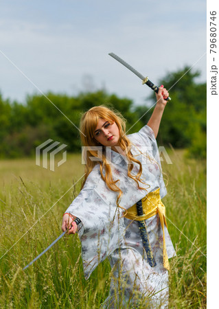 Young asian woman in traditional kimono trains fighting techniques with katana sword Young asian woman in traditional kimono trains fighting techniques with katana sword 79680746