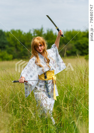 Young asian woman in traditional kimono trains fighting techniques with katana sword Young asian woman in traditional kimono trains fighting techniques with katana sword 79680747