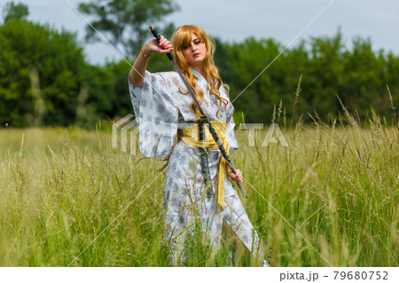 Young asian woman in traditional kimono trains fighting techniques with katana sword Young asian woman in traditional kimono trains fighting techniques with katana sword 79680752