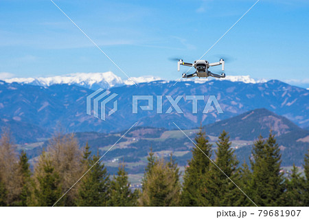 White drone with photo camera flying in the blue sky and beautiful mountain landscape in the background 79681907