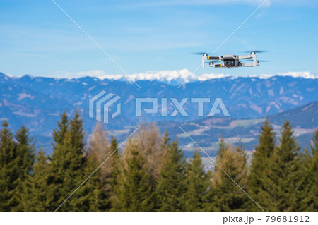 White drone with photo camera flying in the blue sky and beautiful mountain landscape in the background White drone with photo camera flying in the blue sky and beautiful mountain landscape in the background 79681912