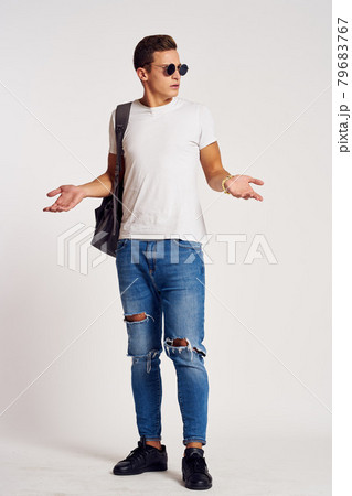 a man with a backpack on his back in jeans t-shirt full length sneakers and glasses on his face 79683767