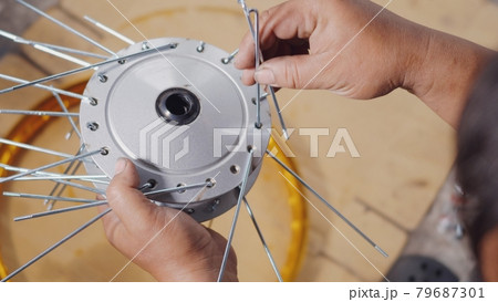 Technician man working motorcycle wheel has spokes weave up on mechanic new steel wheel 79687301