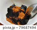 Grass jelly topped with brown sugar in white cup and a silver spoon. No crushed ice.  79687494