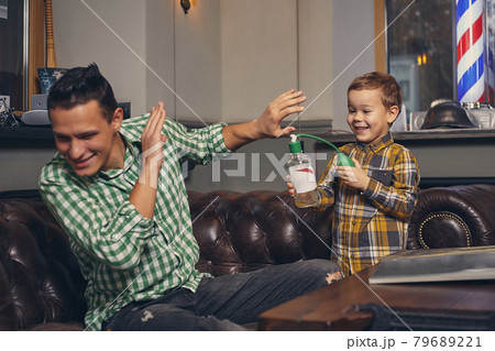 Young father and his stylish little son in the barbershop in the waiting room. 79689221