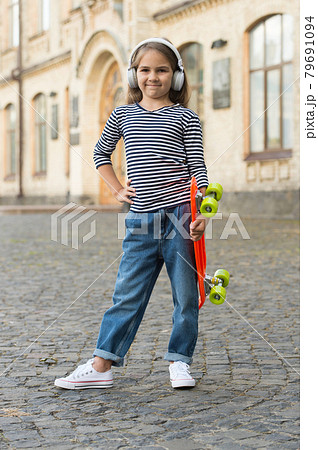 Little girl hold penny board listening to music in modern Little girl hold penny board listening to music in modern 79691094