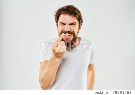 Emotional bearded man in a white t-shirt gestures with his hands light background Emotional bearded man in a white t-shirt gestures with his hands light background 79691562