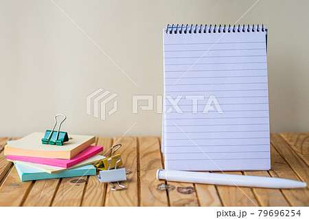 Empty Spiral Notepad With Pen Beside A Stockpile Of Sticky Notes On Top Of A Desk. Blank Notebook With A Ballpen And Stacks Of Note Placed On A Wooden Table. 79696254