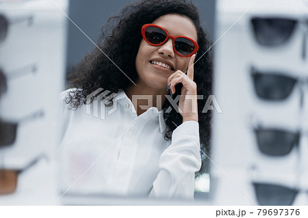 smiling young woman trying on sunglasses in an optometry store. 79697376