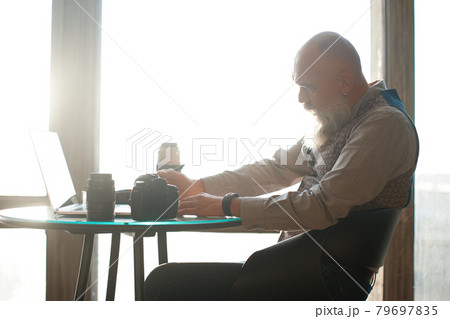thoughtful male photographer works sitting at a table in a cafe . thoughtful male photographer works sitting at a table in a cafe . 79697835