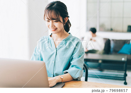 テレワークをする女性とソファでくつろぐ男性 79698657
