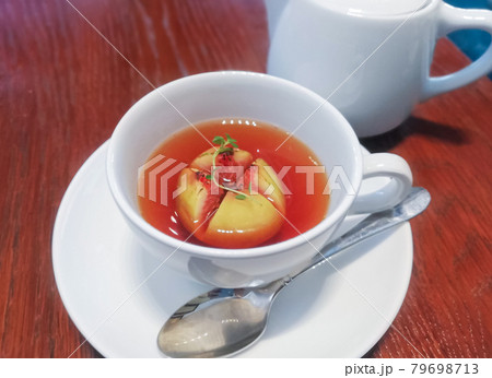 カフェの木製テーブルに乗せられたティーカップ、丸ごと果実が入ったイチジクのフルーツティー 79698713