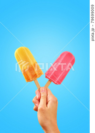 Two color popsicles in woman hands on blue background Two color popsicles in woman hands on blue background 79699009