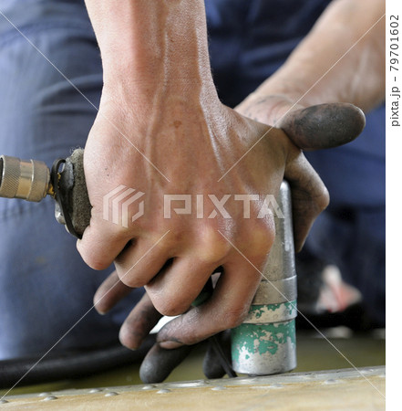 Worker hands making holes with a pneumatic drill on the body plane for further riveting Worker hands making holes with a pneumatic drill on the body plane for further riveting 79701602